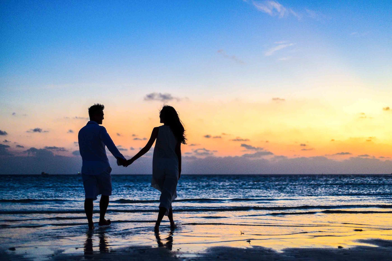 man en vrouw houden hand vast op het strand