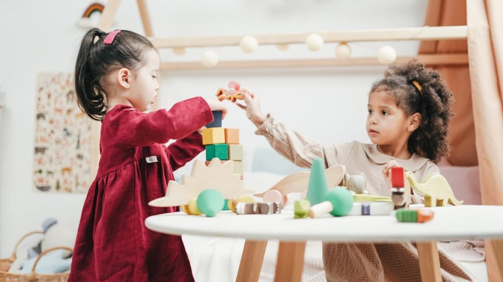 Twee jonge kinderen bouwen met houten speelgoedblokken in een veilige speelruimte van een kindveilig huis