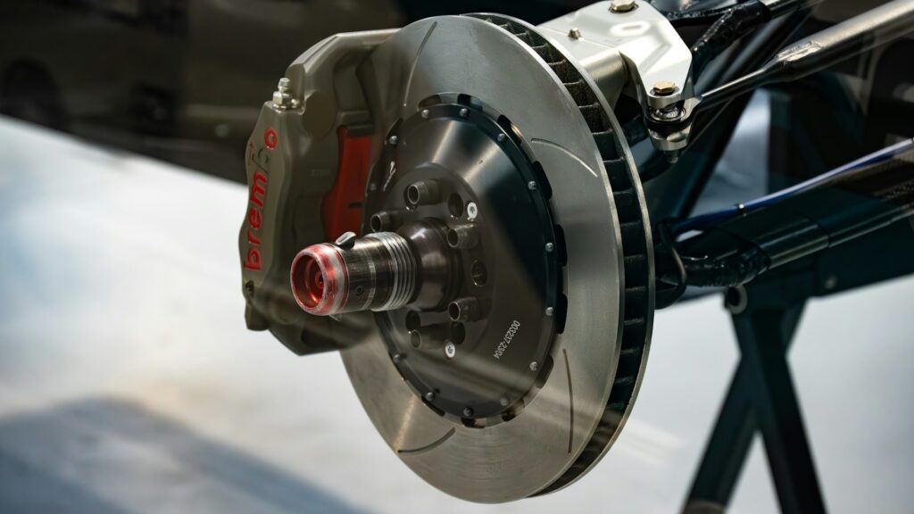Brembo remsysteem met schijf en remklauw in focus, zichtbaar op een geavanceerde racewagenonderstel.