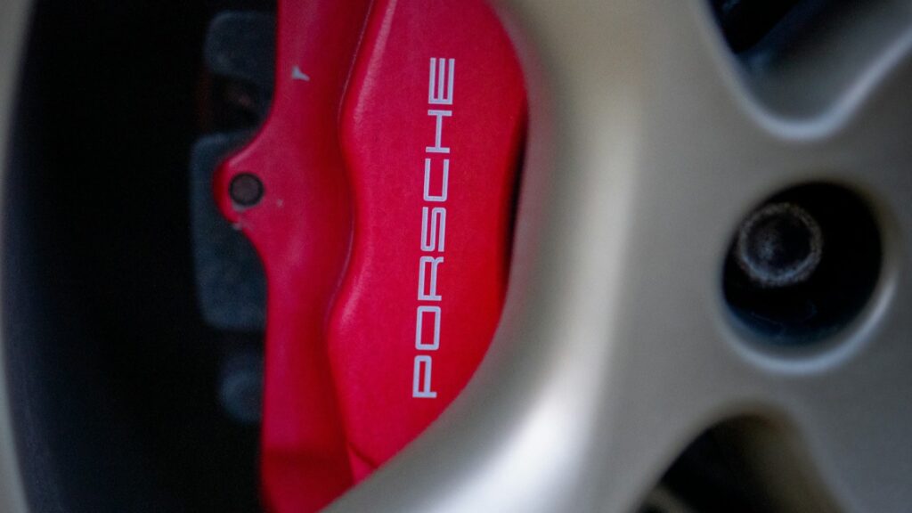 Close-up van een Porsche remklauw, duidelijk zichtbaar op een sportwagenwiel, benadrukkend de premium kwaliteit van het remsysteem.