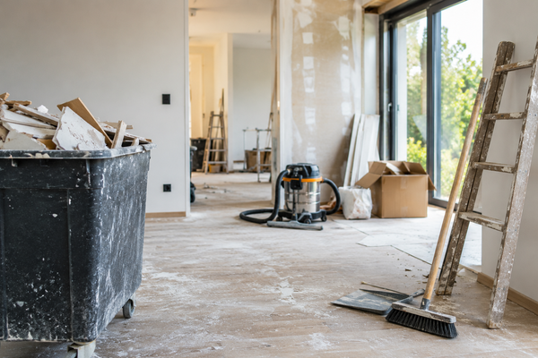 Woning na een verbouwing met bouwafval, schoonmaakmateriaal en stofzuiger tijdens het opruimen en schoonmaken van de ruimte